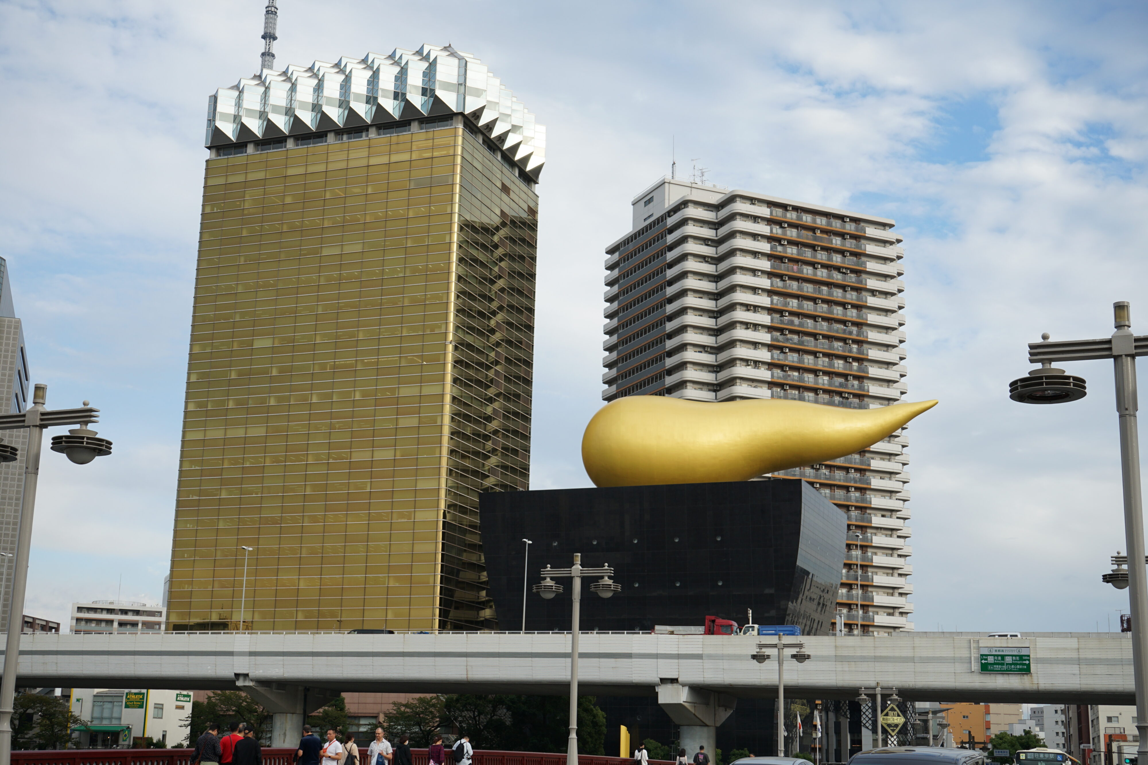 Asahi Building: ein goldenes Hochhaus mit einem wie eine Schaumkrone anmutendes Dach und daneben ein kleineres schwarzes Gebäude mit einem goldenem Gebilde auf dem Dach, dass wie eine Rübenform hat.