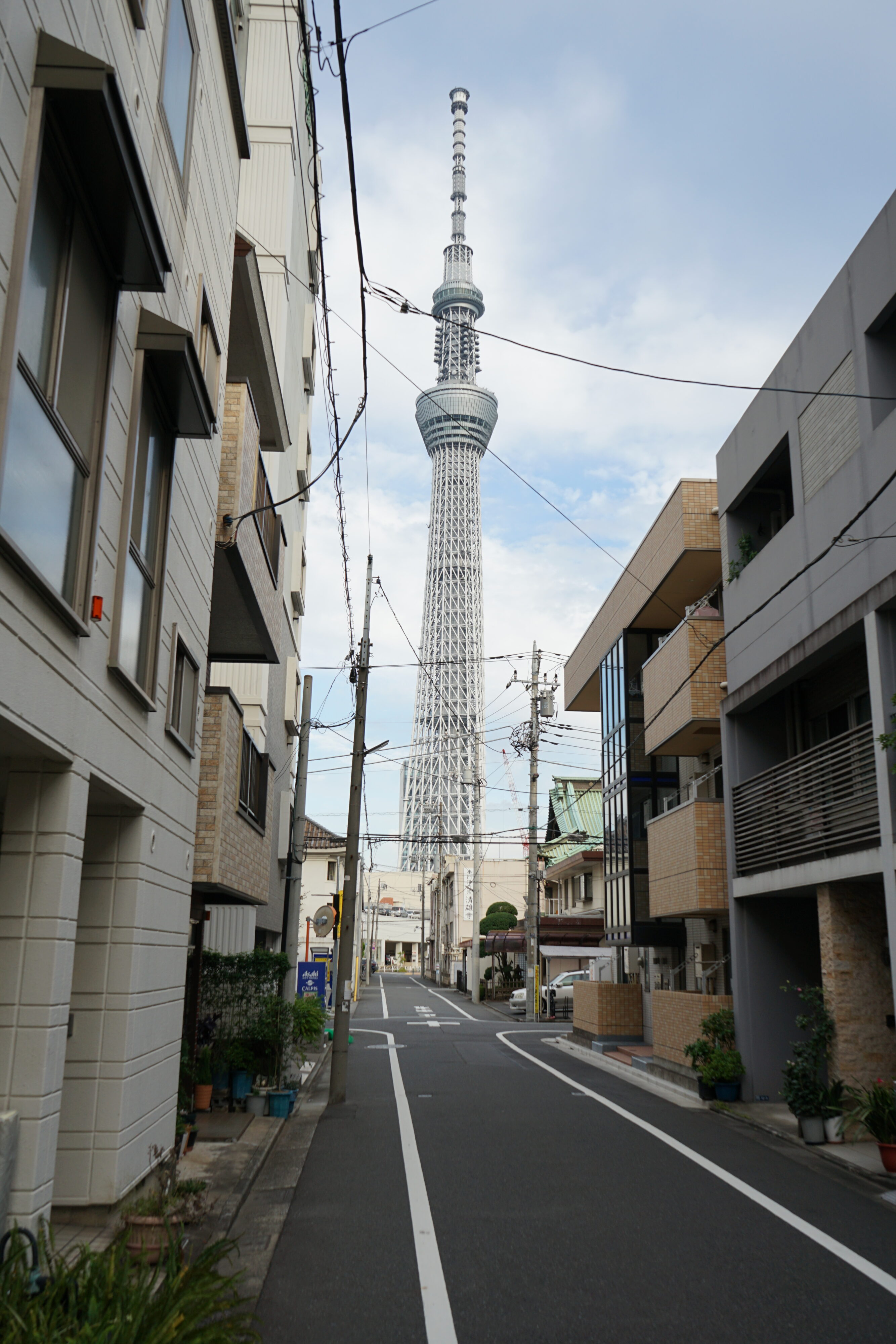 Eine Straße mit kleinen Gebäuden und im Hintergrund der Tokyo Skytree.