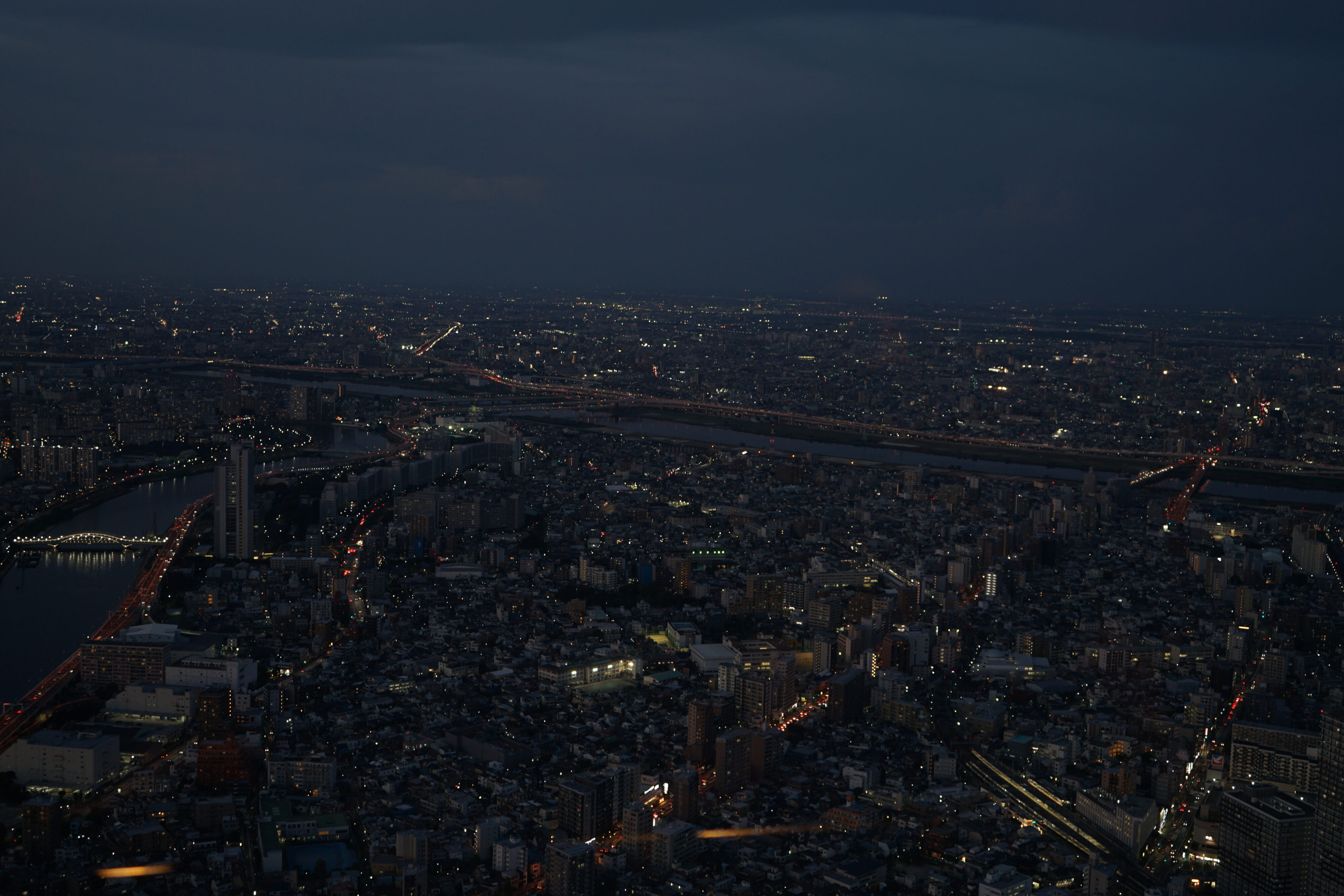 Blick auf Tokyo von oben bei Nacht mit leuchtenden Brücken.