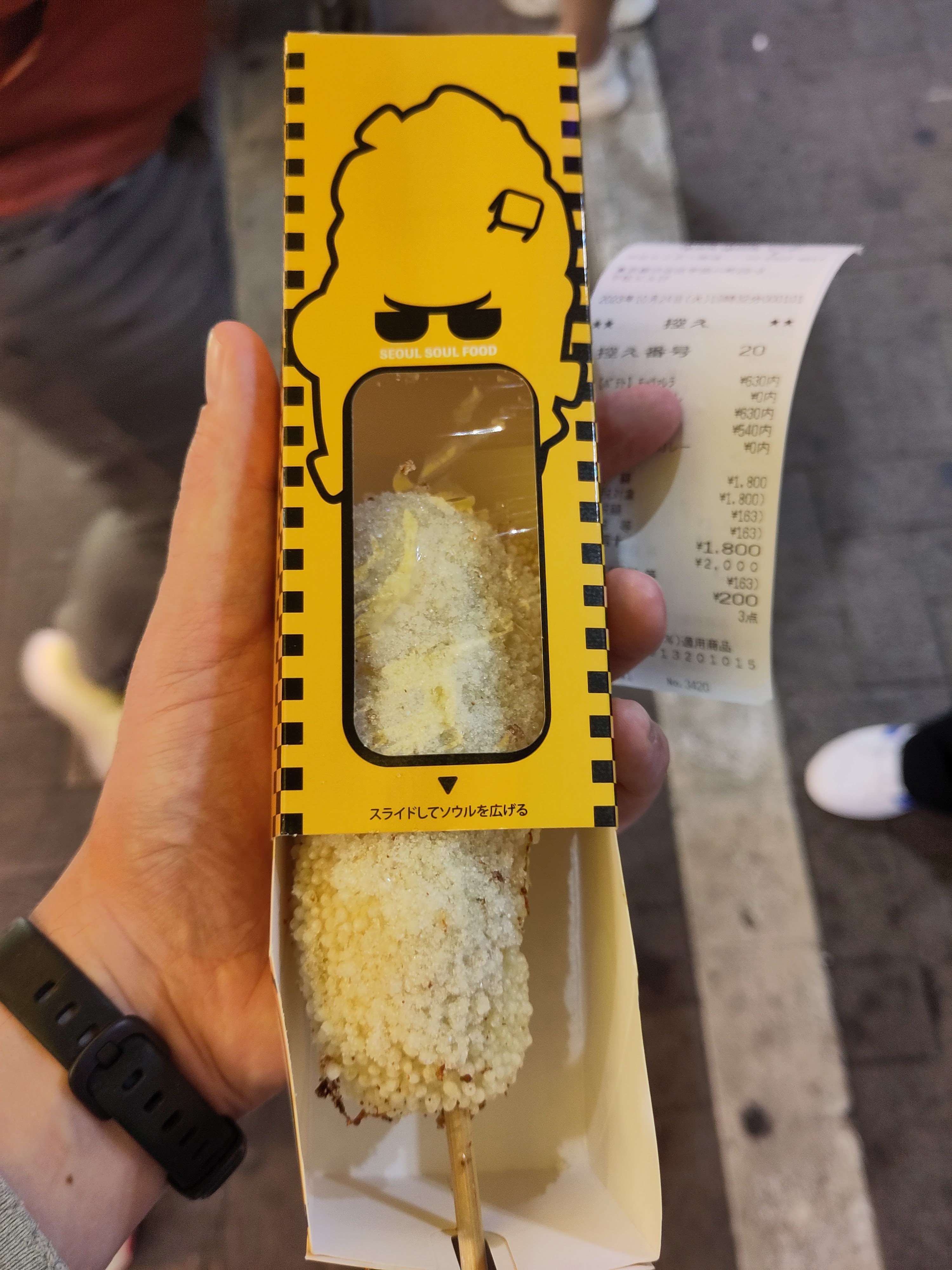 Koreanischer Corn Dog mit Zucker umhüllt in einer gelben Verpackung.  