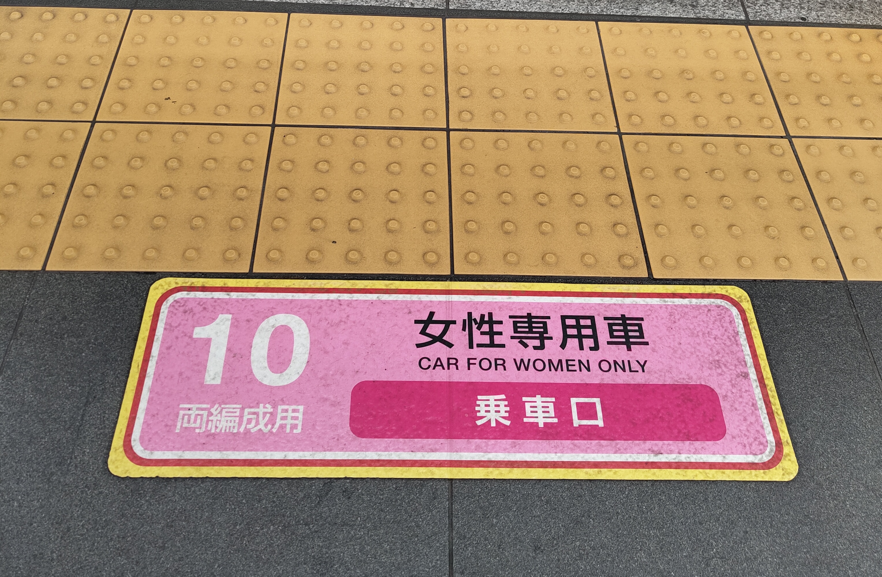 Rosa Aufkleber auf dem Boden des Bahnsteigs auf dem "Car for women only" steht.