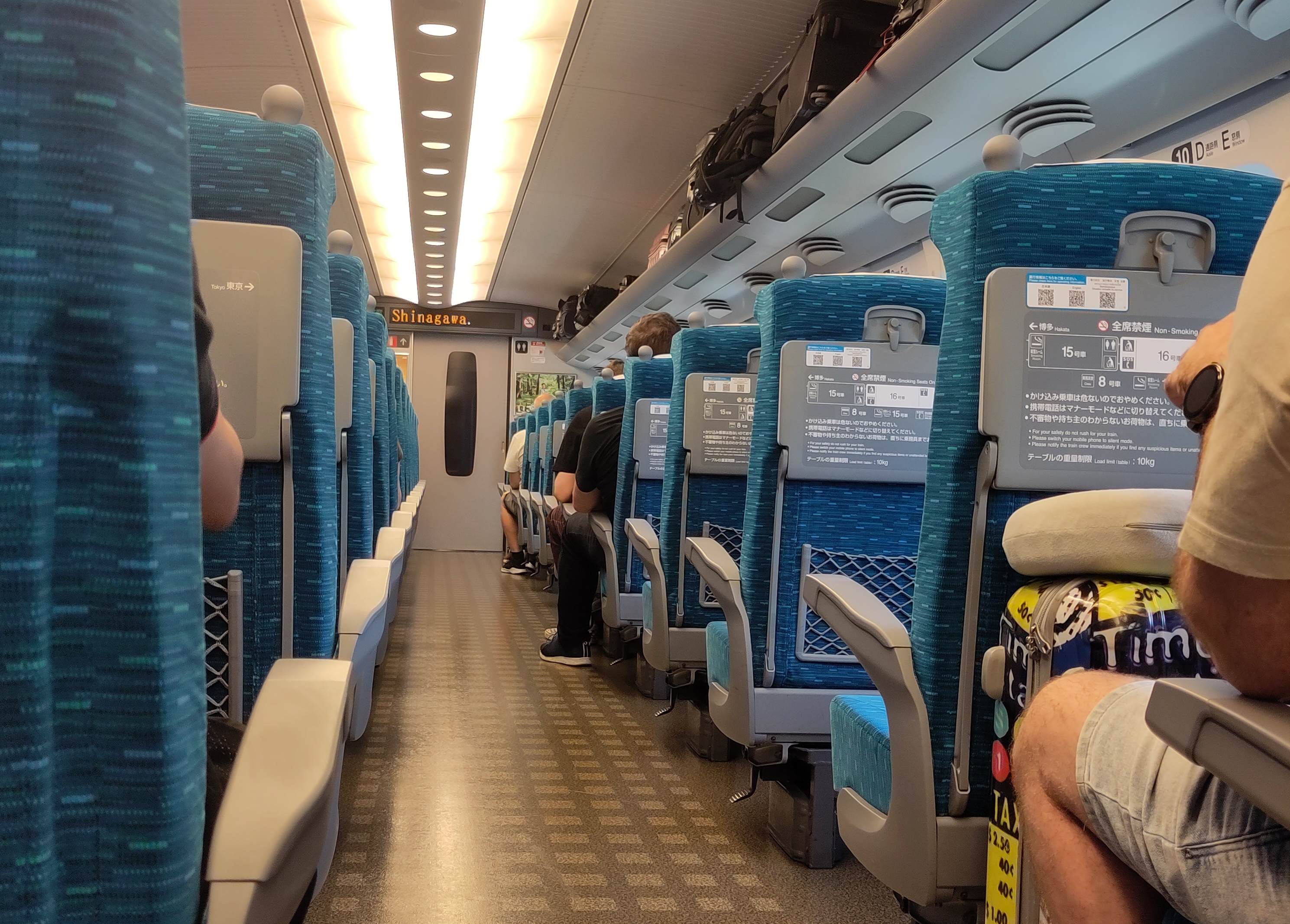 Blick in den Shinkansen-Wagen: Blau-grüne Sitzreihen und ein breiter Gang.