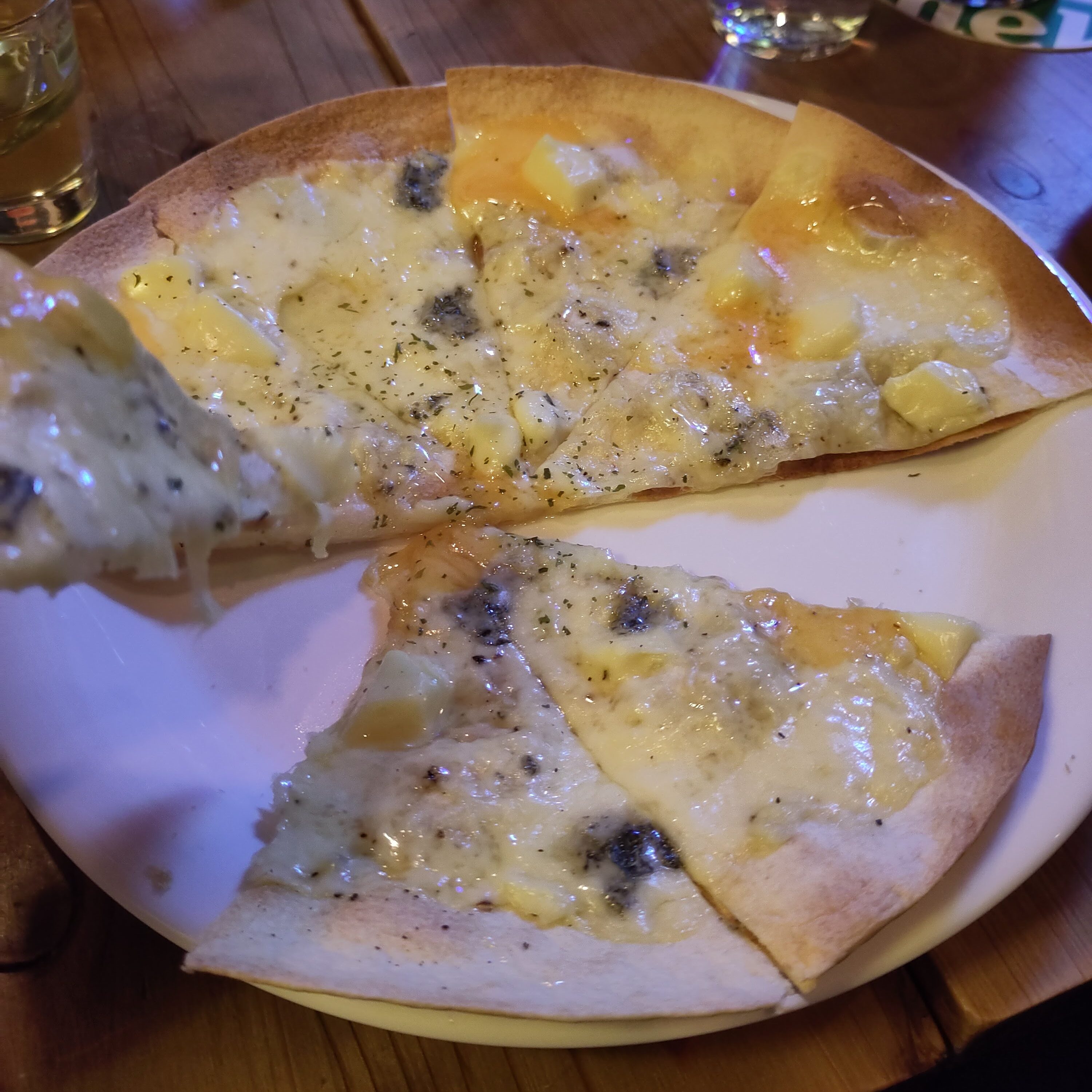 Käsepizza auf einem Teller, bei der schon zwei Stücken fehlen.