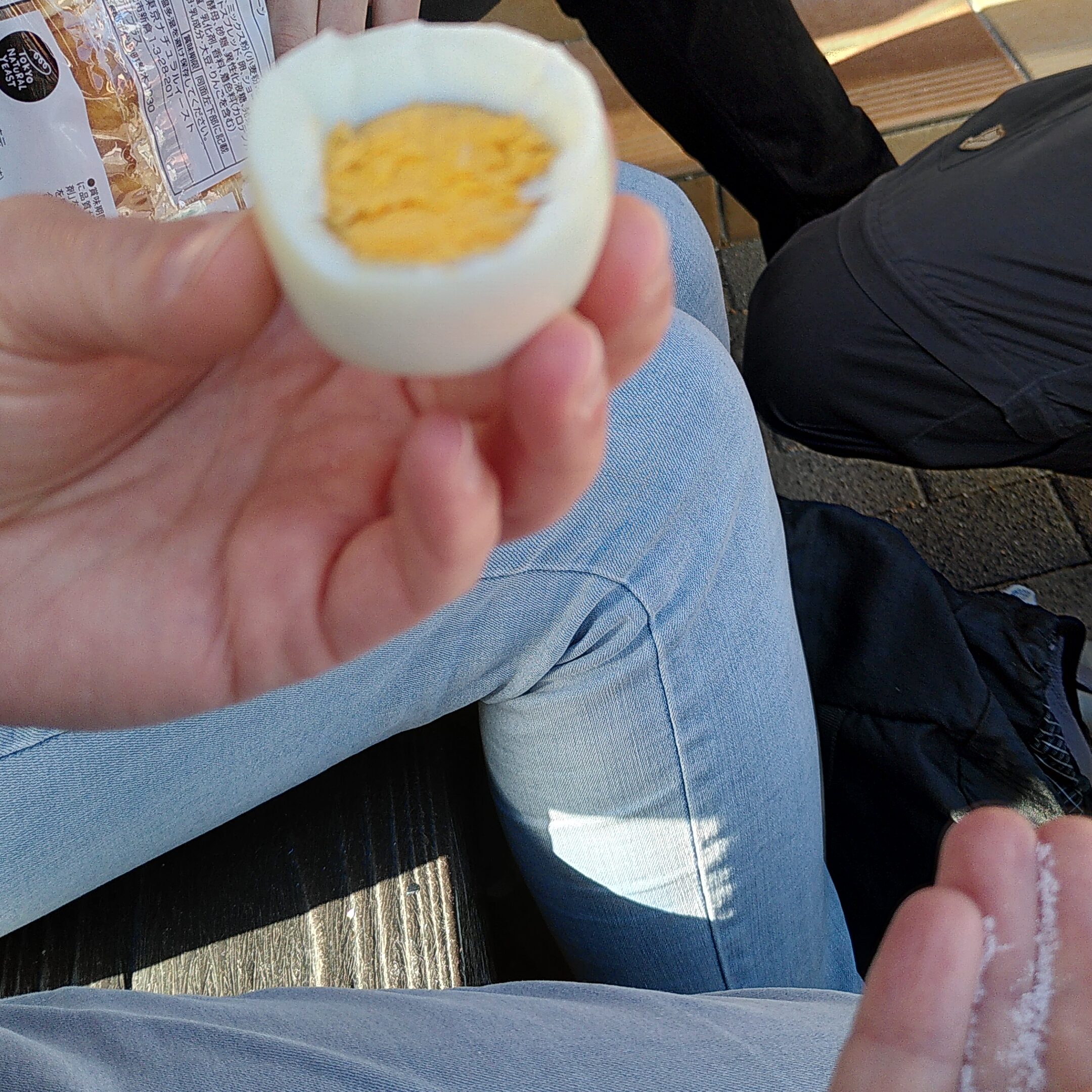 Eine Hand hält ein gepelltes halbiertes Ei mit Eigelb und weißem Eiweiß.