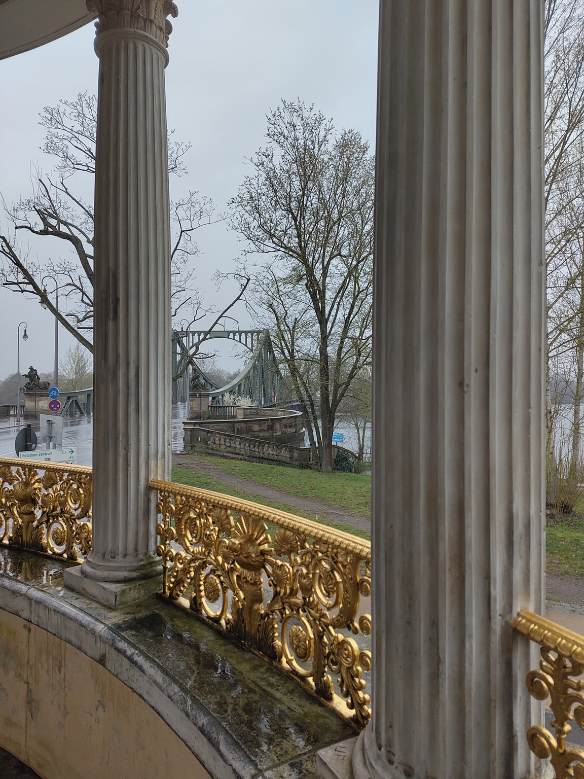 Säulen und vergoldete Balustrade der Großen Neugierde und im Hintergrund die Glienicker Brücke und die Havel.
