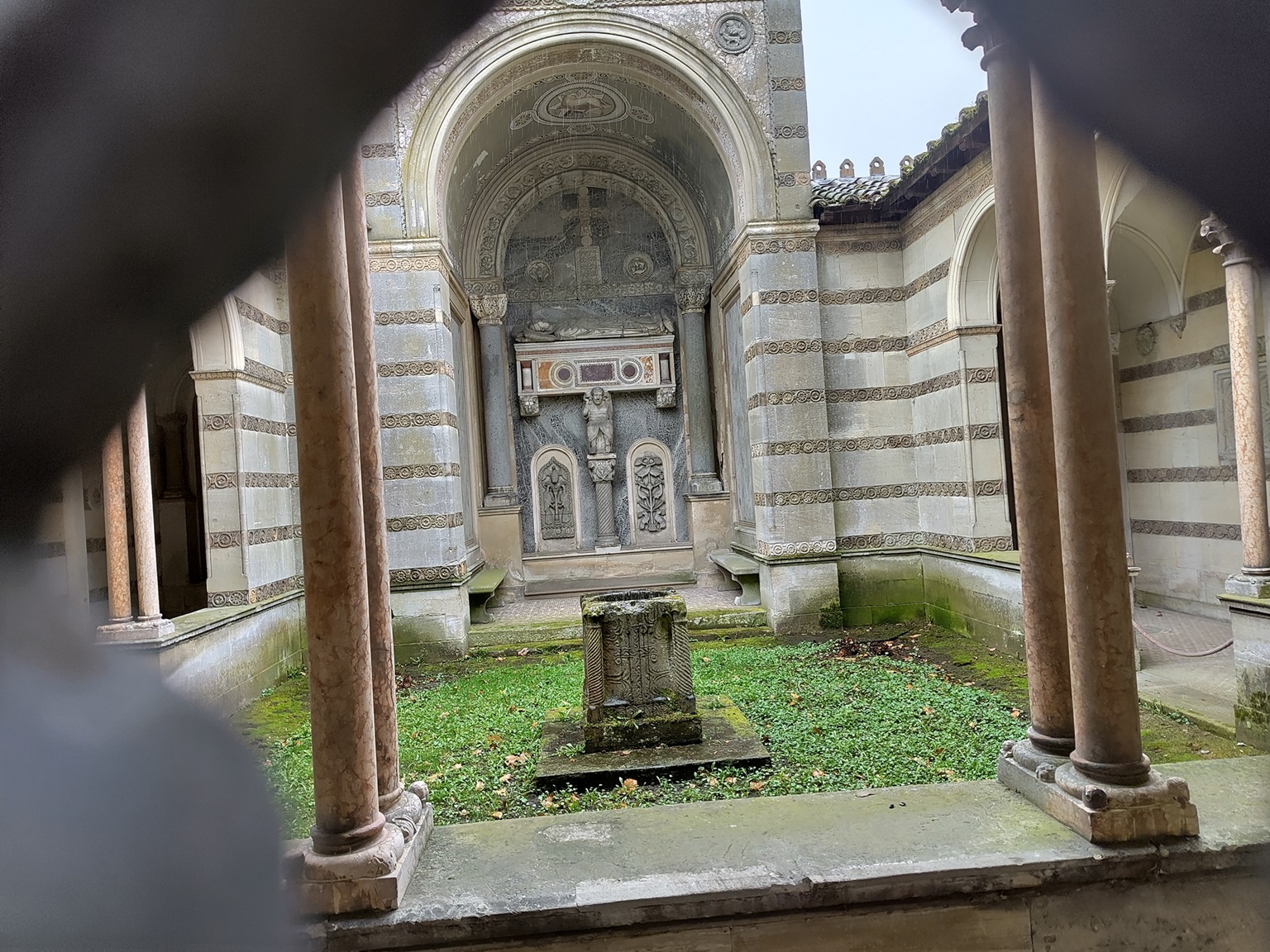 Blick in den Innenhof des Klosterhofes: ein Kreuzgang ist zu erkennen, Mosaike und eine Grabplatte.
