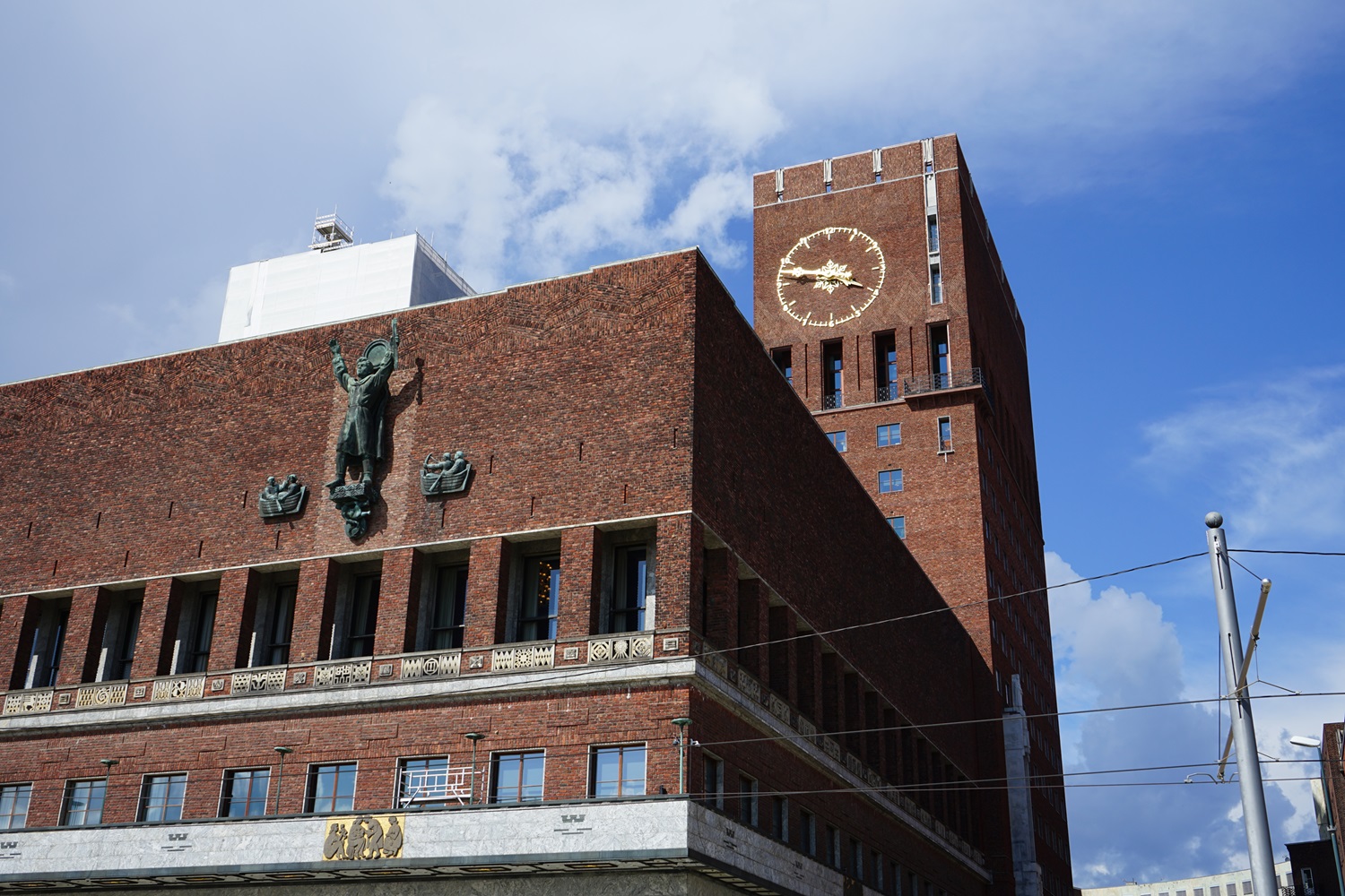 Osloer Rathaus: dunkelroter klobiger Ziegelbau mit Figuren an der Fassade und Uhrenturm.