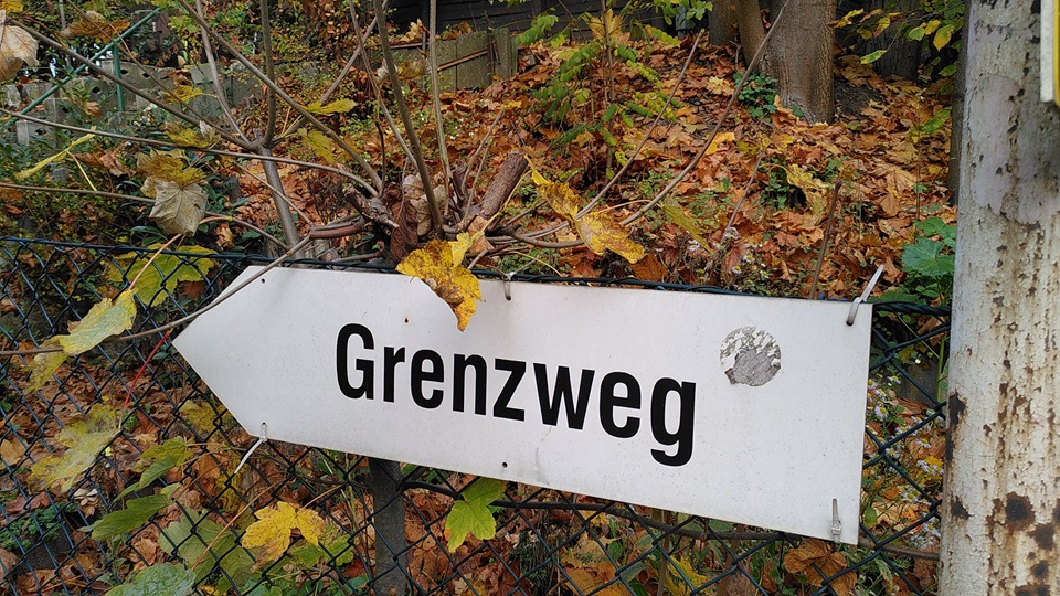 Weißes Schild auf dem "Grenzweg" steht.