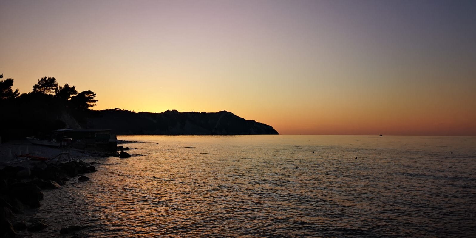 Blick auf das Meer und eine Landzunge in der Abenddämmerung.