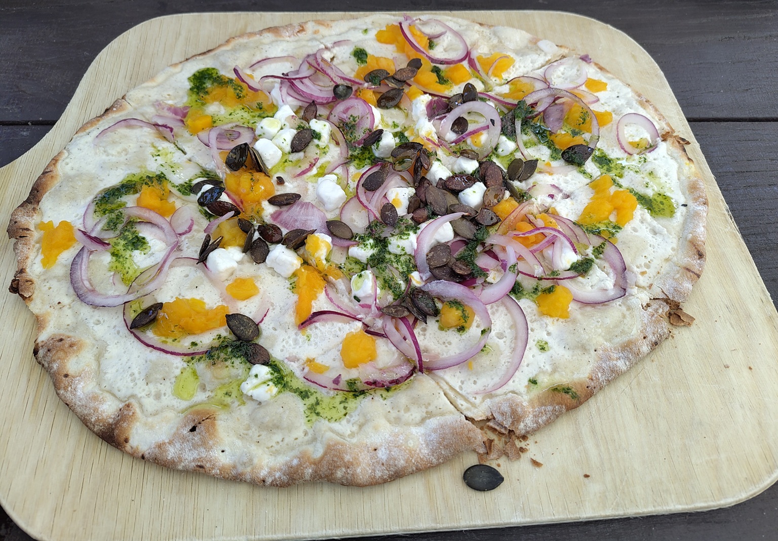 Flammkuchen mit Zwiebeln, Pesto, Kürbis, Kürbiskernen und Feta.