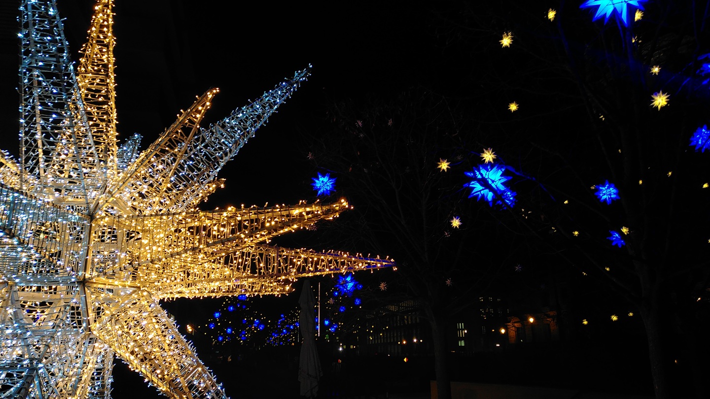 Eine leuchtende Sternskulptur. Im Hintergrund leuchten weitere blaue Sterne