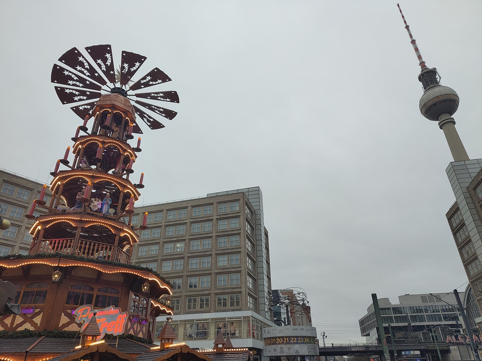 Holzpyramide, Weltzeituhr, Fernsehturm und umliegende Häuser auf dem Alexanderplatz.