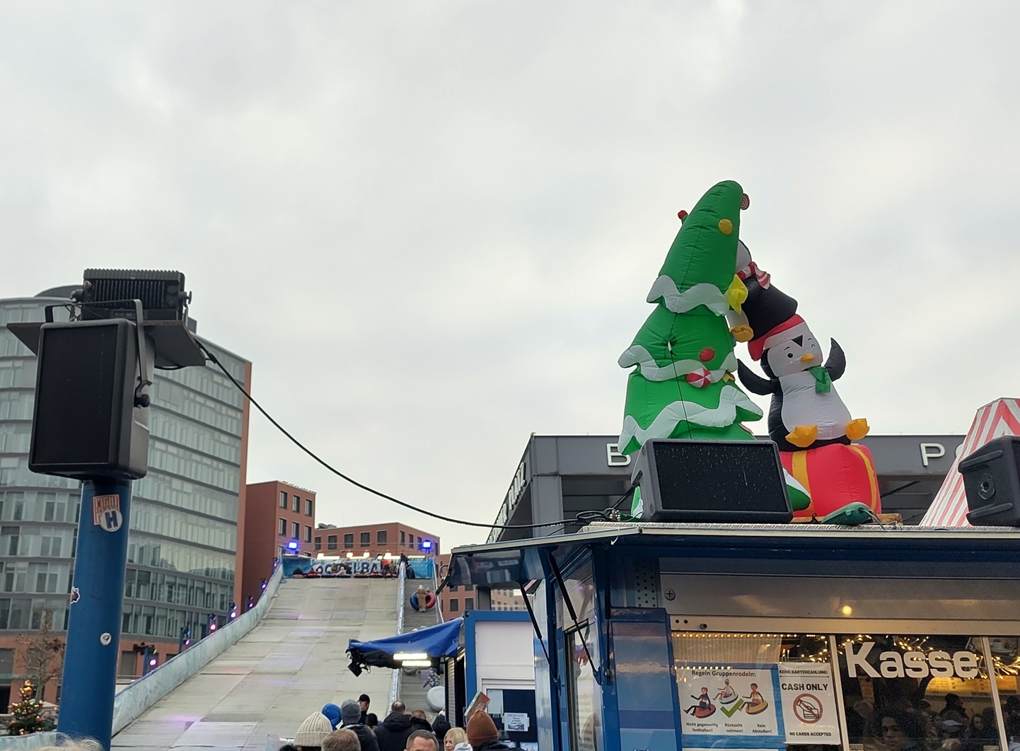 Blick auf die "Rodelbahn" und die Treppe hinauf. Im Vordergrund die Kasse mit einem aufgeblasenen Weihnachtsbaum und Pinguin als Deko auf dem Dach.
