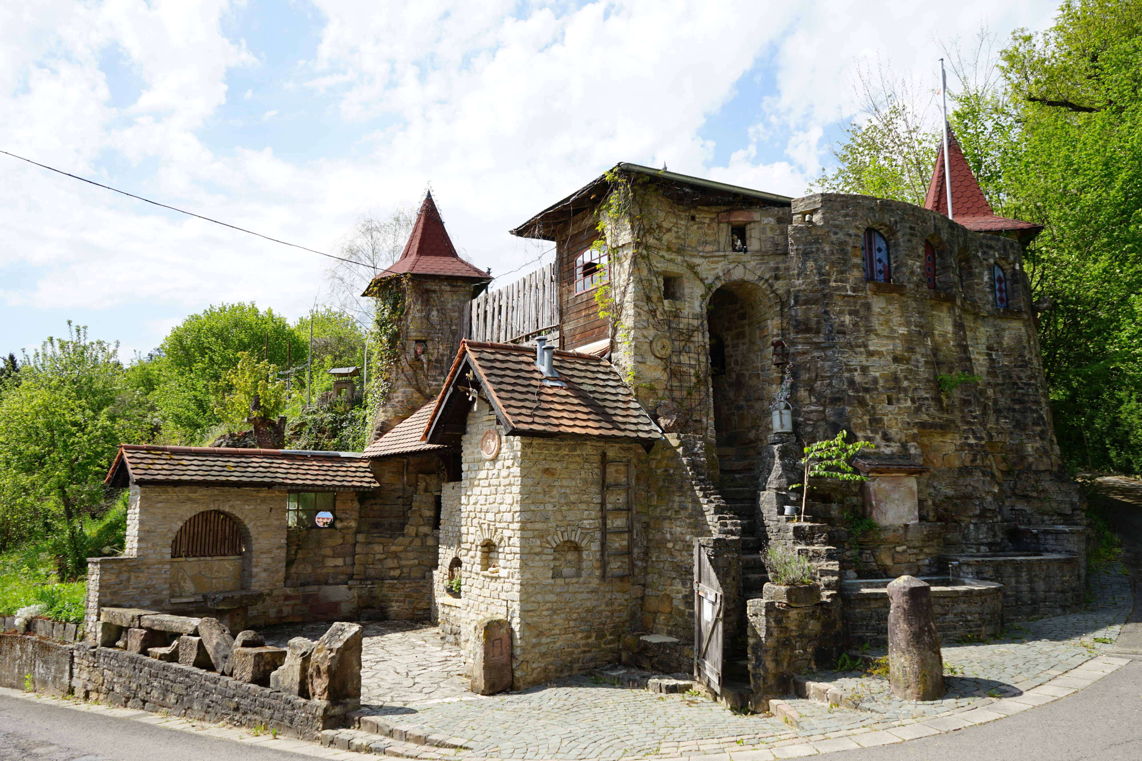 Ein gemauertes Haus mit Türmchen und Giebeln, das wie ein Märchenschloss aussieht.