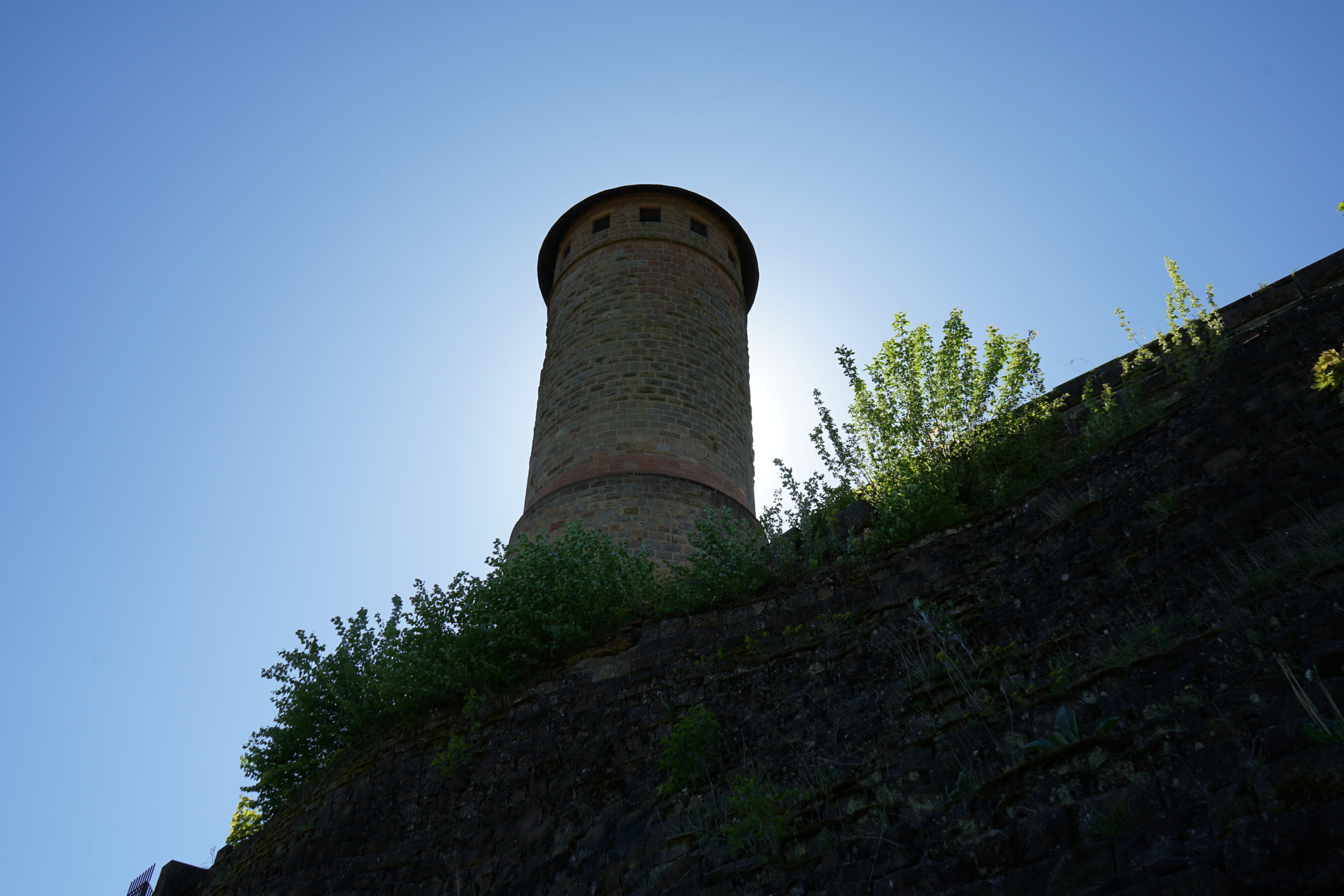 Blick auf einen steinernen Turm und eine Steinmauer.